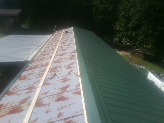 Old rusted panels beside newly installed green metal roofing — Wind Damage Roof Repair by Roofing Brothers in Woodruff