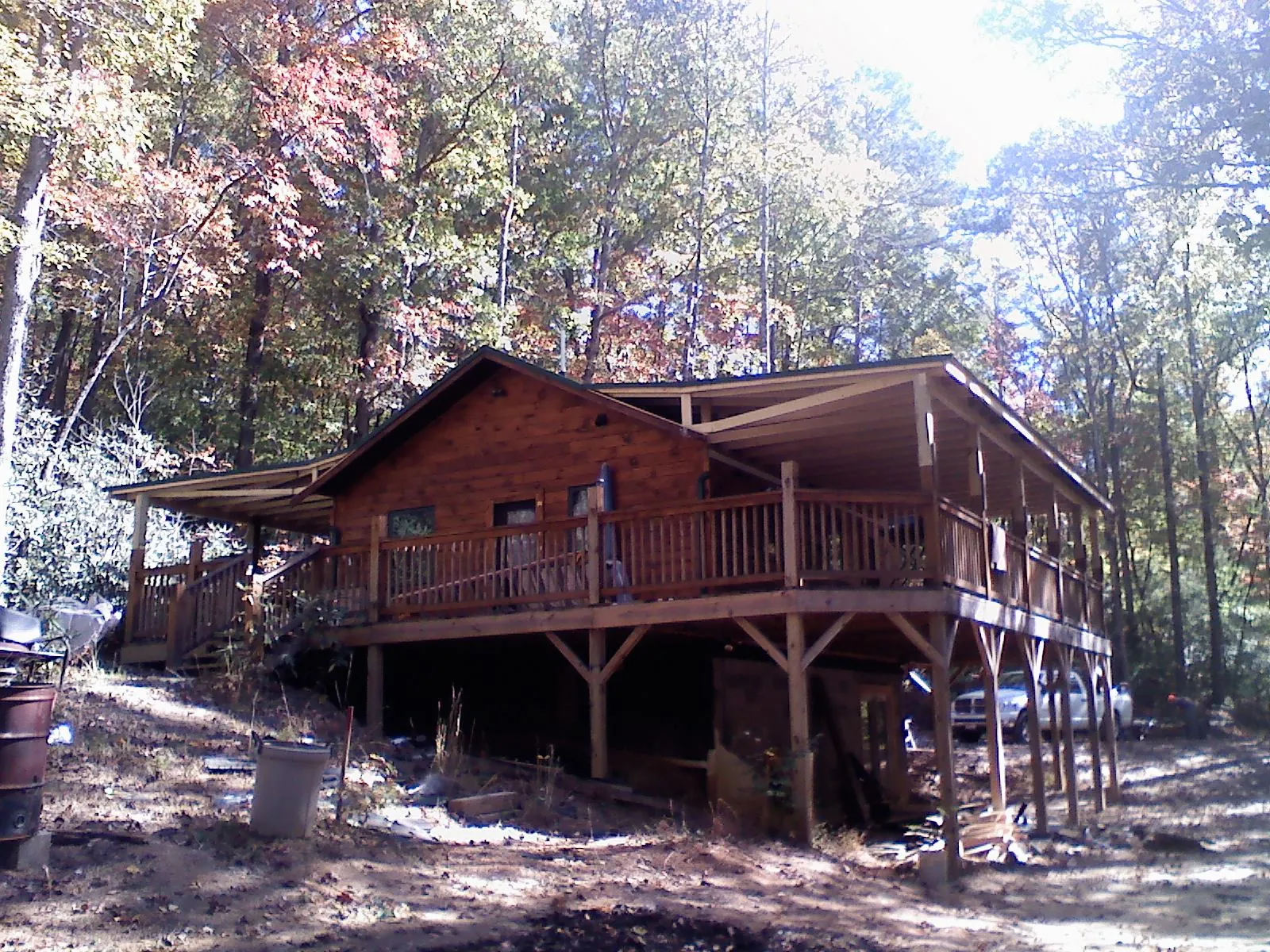 Log cabin with a wraparound porch and metal roof in the fall in Woodruff
