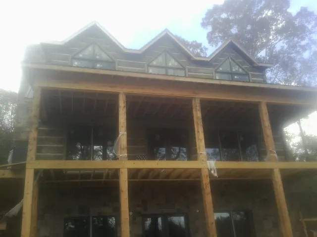Dormers and porch framing on a large log home under construction — Roof Coating work by our crew in Woodruff
