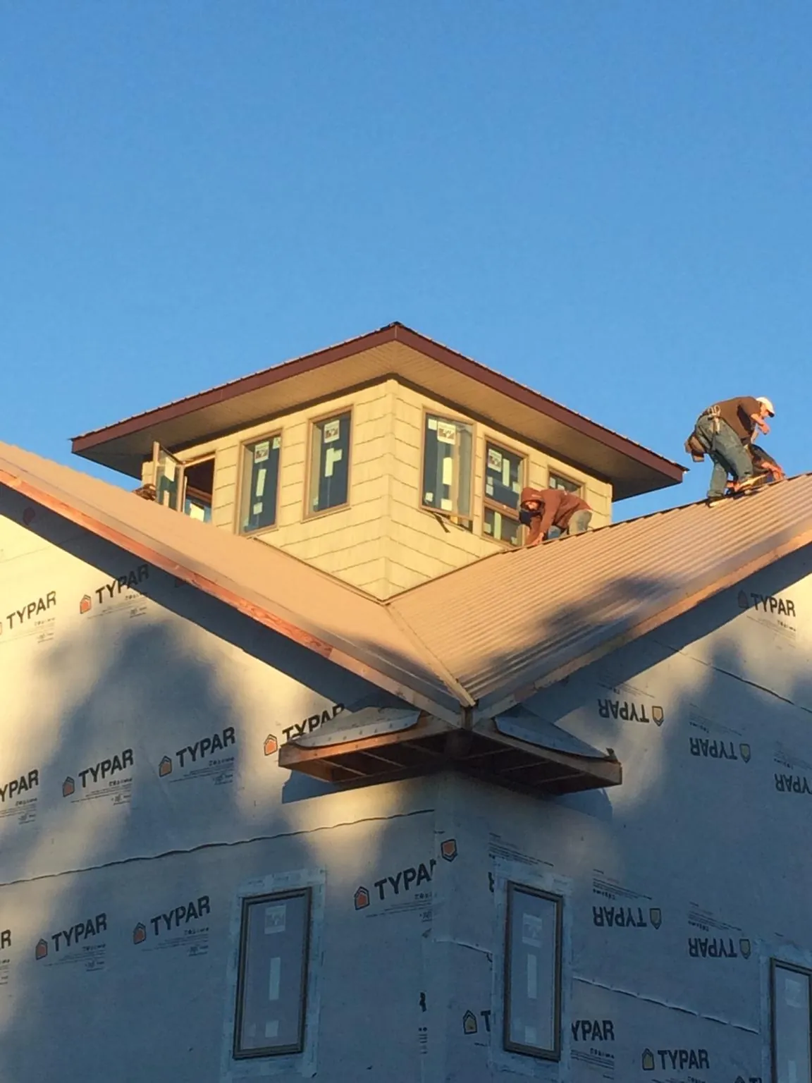 Roofers working around a rooftop cupola on a new metal roof at sunset — Roof Waterproofing in Woodruff by Roofing Brothers